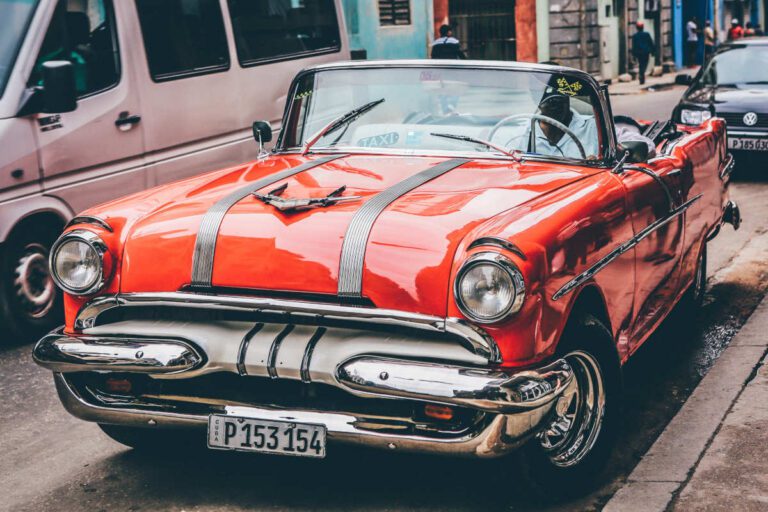 Very shiny orange vintage car parked on a street